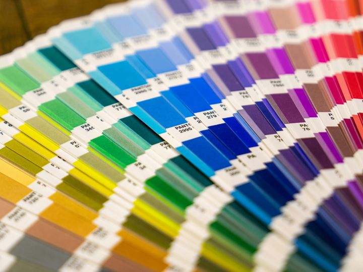 Close-up of a colourful Pantone swatch book, displaying a wide range of colour samples arranged in gradient order, from yellows and greens to blues and purples.